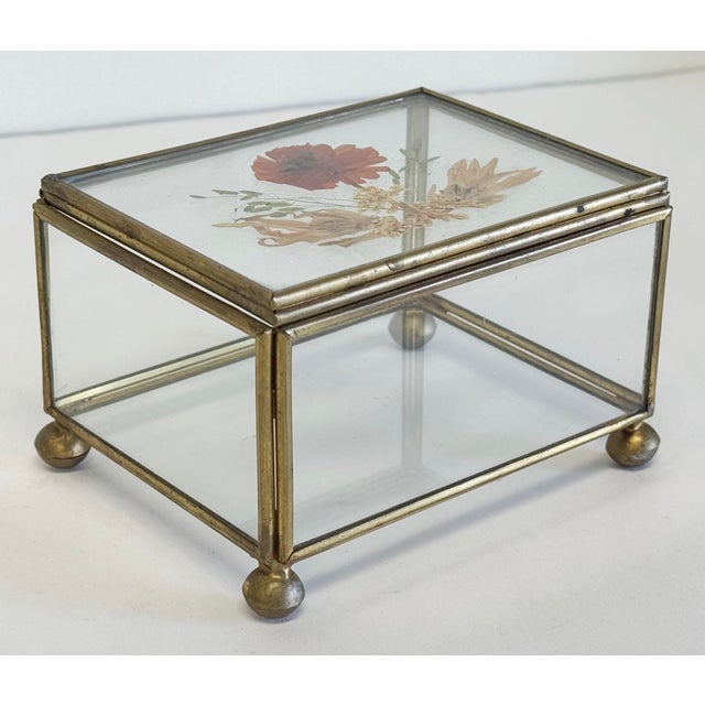 Vintage glass and brass lidded display or trinket box featuring pressed flower arrangement to lid. Supported by four brass...