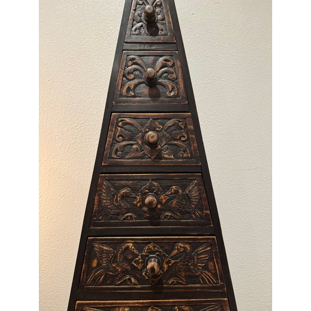 This striking Indonesian style pyramid chest of drawers features 11 graduated drawers with hand-carved bird and floral...