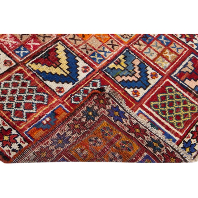 Beautiful vintage Persian Heriz hand-knotted wool rug with a red color field. This piece has a beige frame and multicolor...