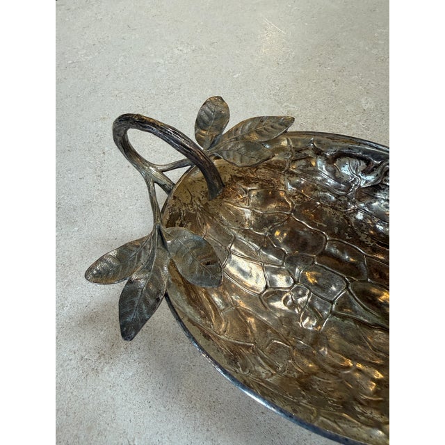 A sculptural Italian decorative bowl in silvered metal, designed with a textured surface and raised on small feet,...