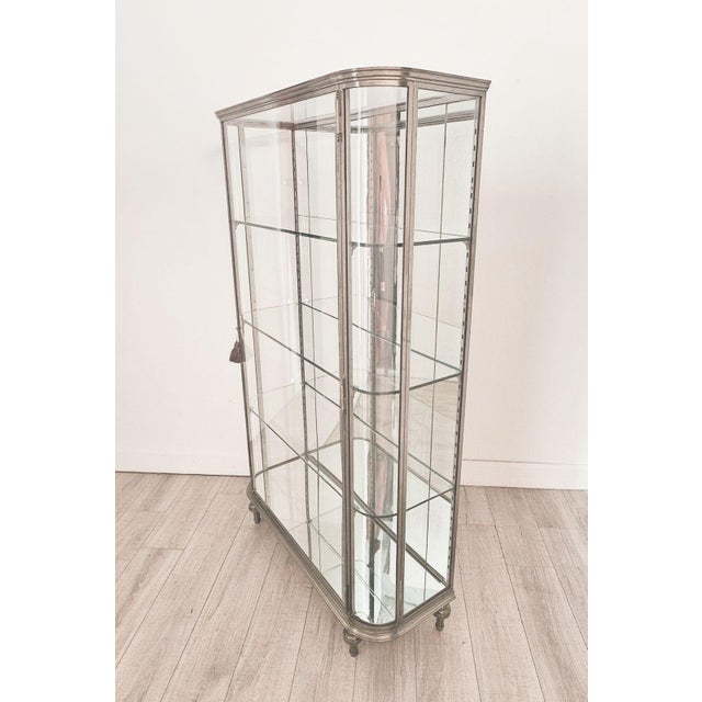 A brushed steel mirrored French display case / vitrine, circa 1920. On turned tapered Louis XVI–style feet. An elegant,...