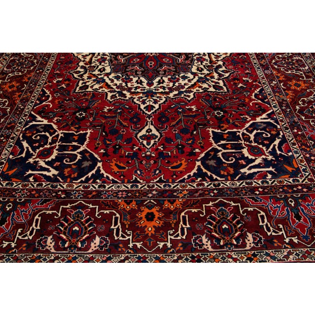 Beautiful Antique Bakhtiari hand-knotted wool rug with a red field. This Persian piece has an all-over multicolor accent...
