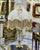 Elegant French-style table lamp featuring a luxurious beige and ivory fabric shade adorned with cascading gold thread...