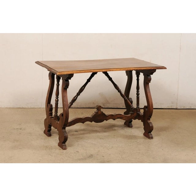 A Spanish walnut wood table with lyre legs from the 19th century. This antique table from Spain features a rectangular-...