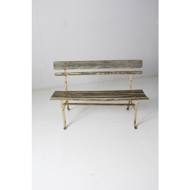 This vintage wood slat bench showcases a pastel yellow metal frame complemented by a wooden slat seat and backrest. Its...