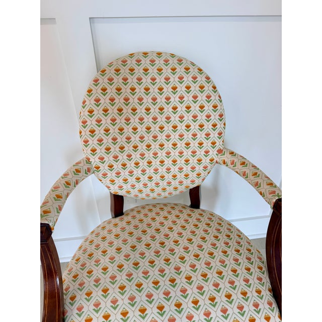 Elegant vintage accent chair featuring a round back, dark wood arms and legs, and a charming tulip-patterned upholstery in...