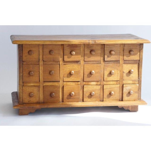 A handmade vintage apothecary cabinet with 18 drawers made out of solid wood. The chest has small round wooden knobs on...