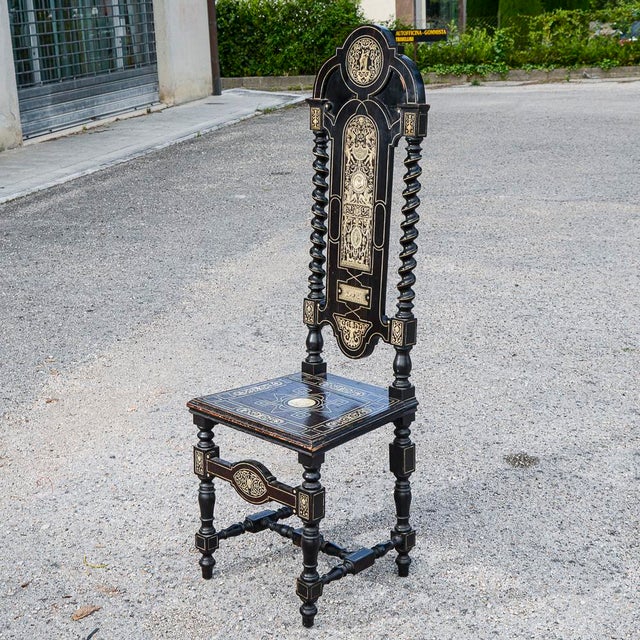 Inlaid chair made of ebony stained wood with backrest framed by twisted columns and decorations also in relief. The...