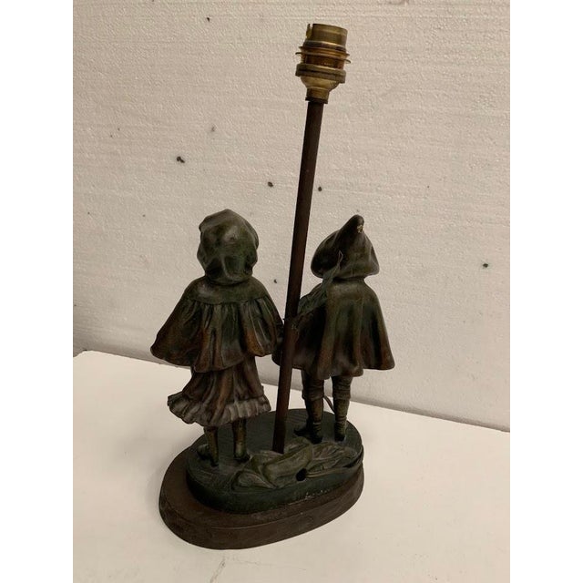 Charming spelter bedside lamp decorated with a motif of two children wearing capes good condition dimensions: h 24 x w 15...