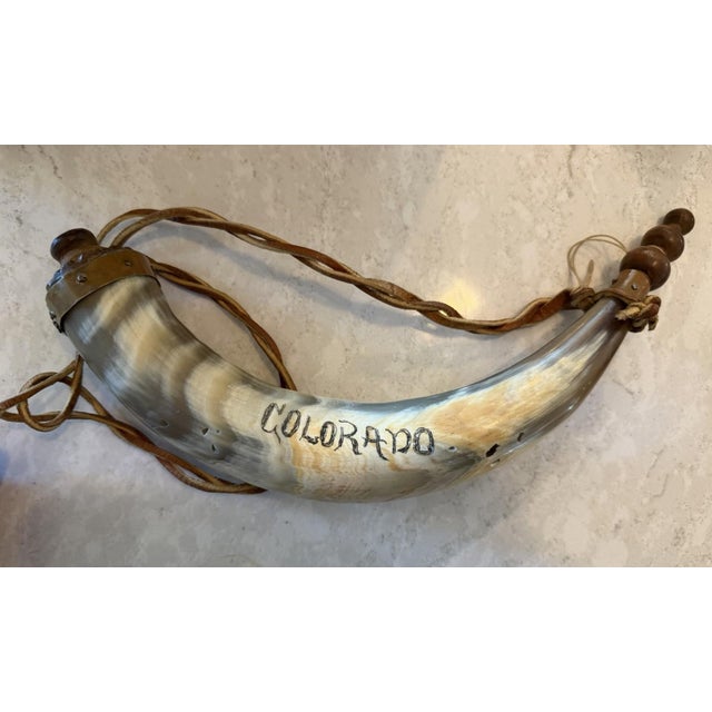 Handmade powder horn crafted from natural horn with a detailed scrimshaw-style deer hunting scene. This piece features a...