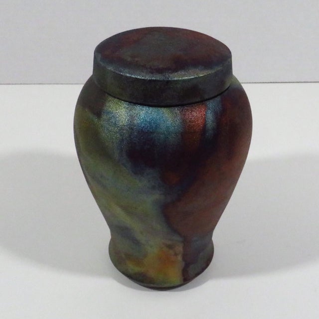 Handmade "Meiping" (plum-shape) raku glazed lidded jar. The firing produced vivid metallic colors of gold, blue, green and...