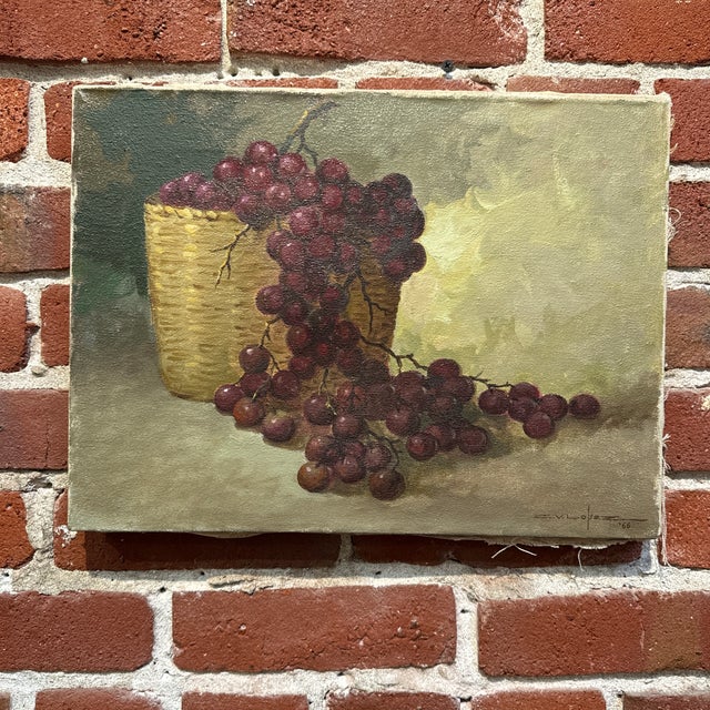 Vintage 1966 Oil painting depicting a still life of purple grapes in a basket Sign bottom right corner Overall size 16” by...