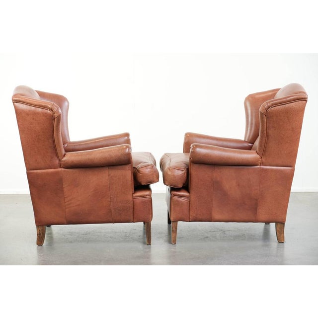 Set of two beautiful English-style cowhide wing armchairs with matching piping and a characterful appearance. : This set...