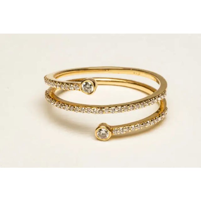 A stylish triple band of 18K gold with round, brilliant cut diamonds in a pave` setting. Each end capped off with a...