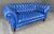 This Custom COCOCO Home blue Chesterfield loveseat features deep diamond tufting, rolled arms, and a bold saturated...