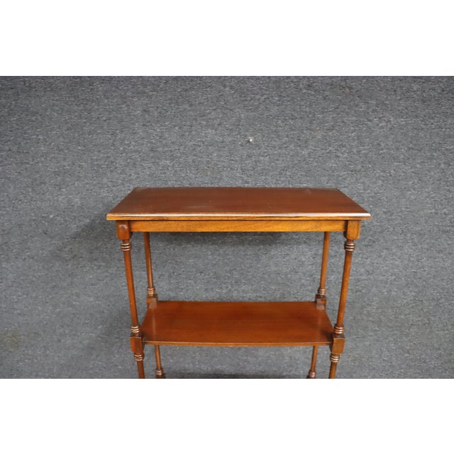 Mahogany etagere by Baker Furniture featuring an open four-shelf design, turned supports, and a molded base with a single...