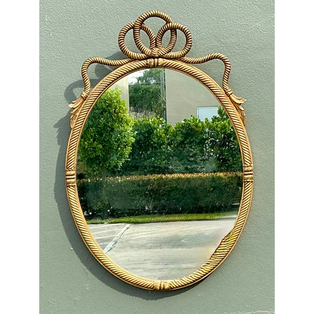 This exquisite vintage wall mirror is a quintessential example of Neoclassical elegance, featuring a charming rope-and-...