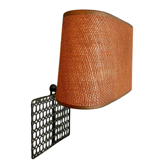 Striking 1970s wall-mounted sconce featuring a pierced metal backplate with a repeating geometric lattice pattern. The...