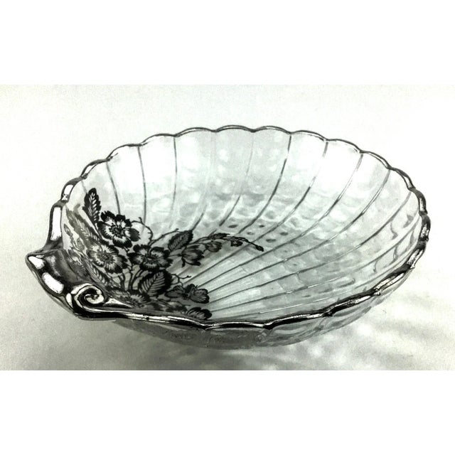 Very unique dish or trinket plate. In the shape of a scallop with silver or silver plate floral scrolls. In wonderful...