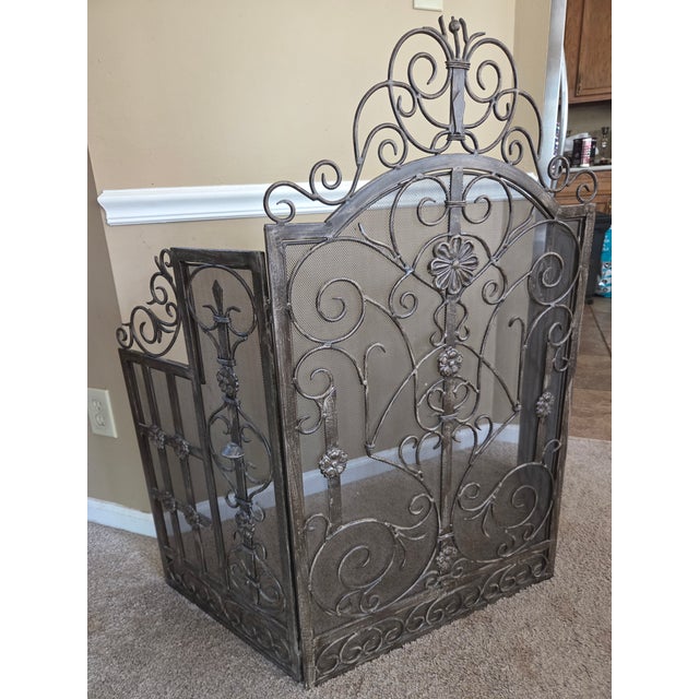 The free standing trifold screen has hinged sides. The heavy metal mesh features an arched top. The front of the screen...