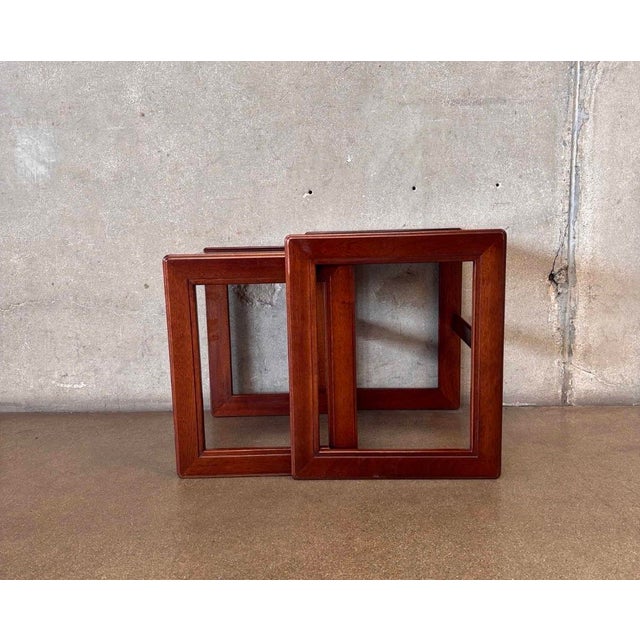 A sleek pair of vintage Mid-Century Modern nesting tables crafted in richly grained teak. Featuring clean, architectural...