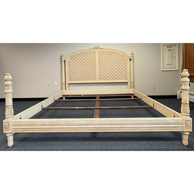 An elegant EJ Victor bed with a tall, arched headboard and an intricate lattice pattern. The warm, antique ivory finish...