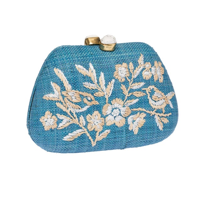 The TAMU clutch is an exercise in sun-soaked glamour, crafted from vibrant blue raffia and exquisitely hand-embroidered...