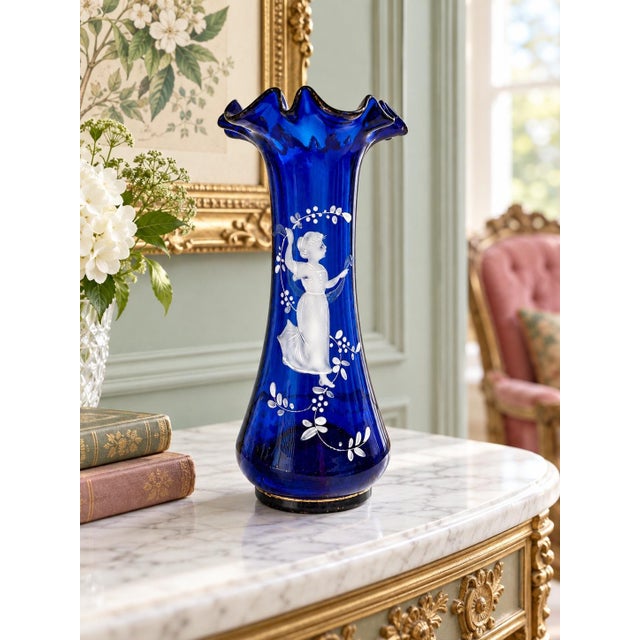 An elegant cobalt blue glass vase featuring white enamel decoration in the Mary Gregory style. A finely detailed female...