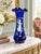 An elegant cobalt blue glass vase featuring white enamel decoration in the Mary Gregory style. A finely detailed female...