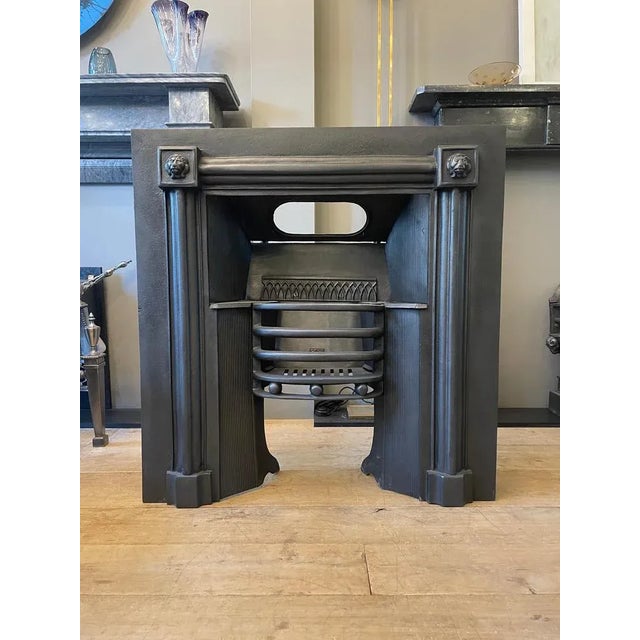 A cast iron register grate/ Fireplace insert in the Regency manner, decorated with Lions masks and inner reeded panels. By...