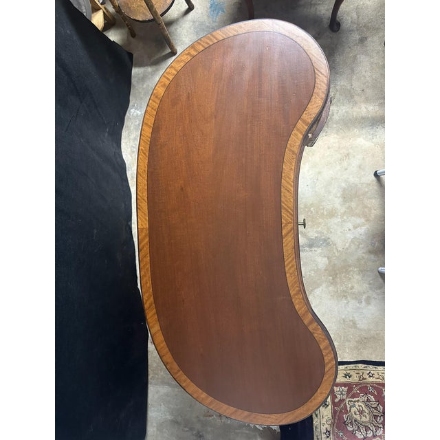 Beautiful vintage kidney-shaped writing desk in the Sheraton Revival style, crafted in rich mahogany with contrasting...