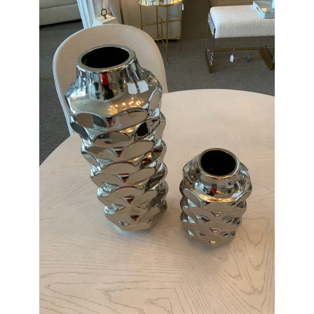 Enhance your living space with this Pair of Metallic Silver Vases, featuring one tall and one short design. These elegant...