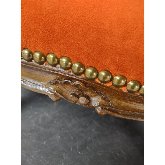 A French Carved Walnut Footstool Newly Updated and Covered in Orange Velvet with Nailhead Trim.