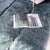 A quietly textured slate grey rug, its plush surface subtly divided by fine vertical lines into soft, uneven panels. The...