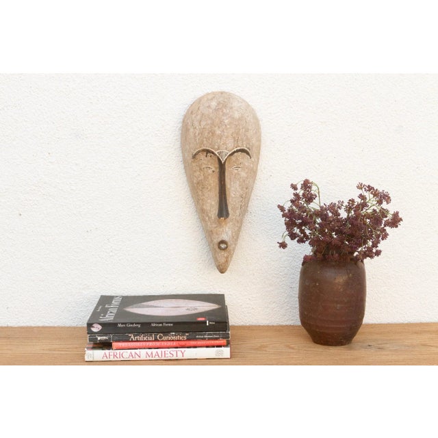 Discover the captivating allure of authentic African art with this vintage hand-carved wooden mask. Imbued with a rich...
