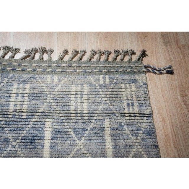 This blue wool rug features a hand knotted pile construction and functions as a durable floor covering for residential or...
