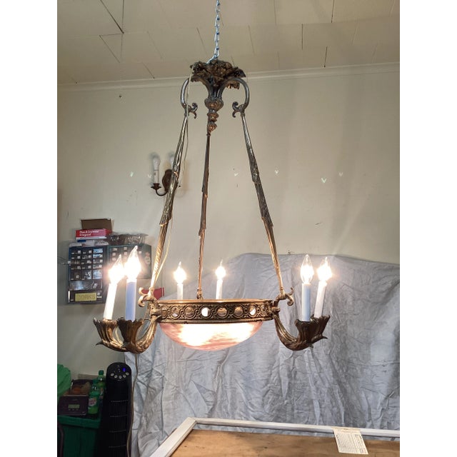 This is a period Art Deco French chandelier. This fixture is imposing with its gilt bronze frame and pink art glass dome...