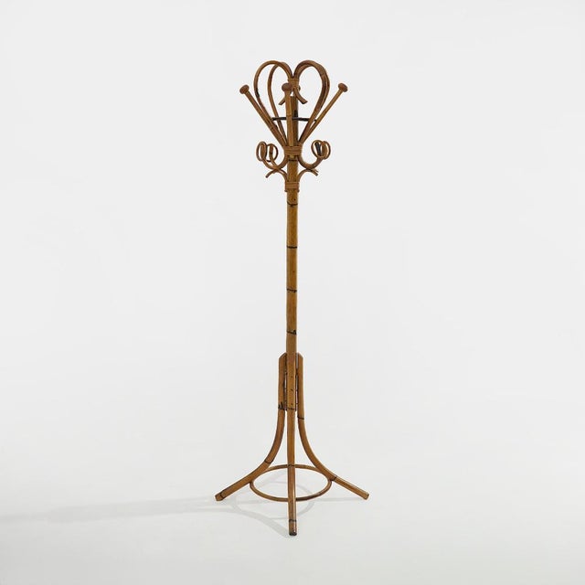 An elegant freestanding coat rack in rattan and woven wicker, embodying the natural and decorative aesthetic that defined...