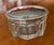 4 1/2" round early 20th century glass powder jar with sterling silver lid. The lid has an embossed pattern circling the...