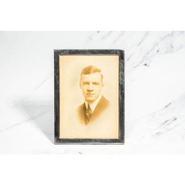 The frame features a refined sterling silver border with clean, sophisticated lines accented by a beautifully engraved...