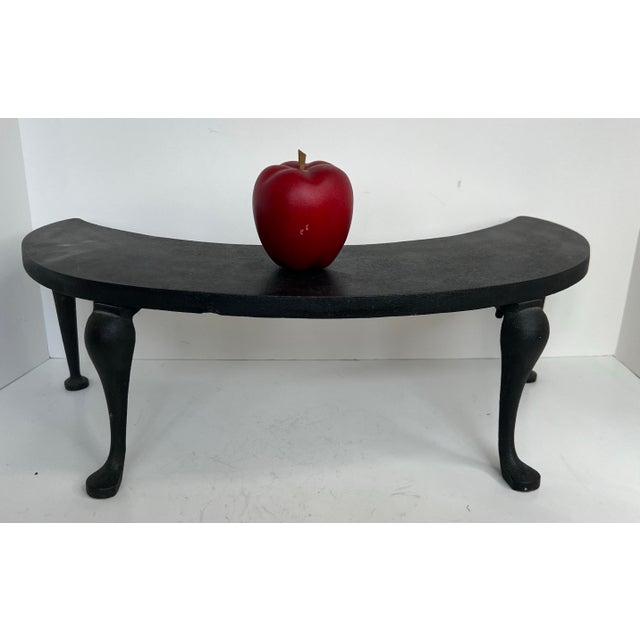A charming antique cast iron fireplace fender warmer featuring a graceful crescent form raised on four cabriole legs....
