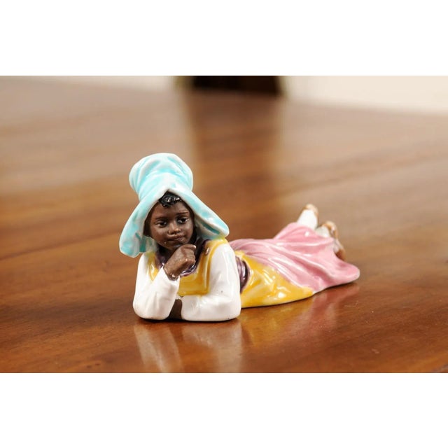 A petite English porcelain figurine from the 20th century, depicting a young farm girl. Created in England during the 20th...