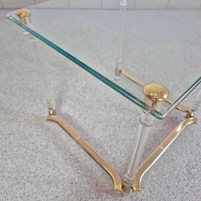 Elegant side table crafted from glass, brass-plated metal, and decorative acrylic elements. The combination of luxurious...