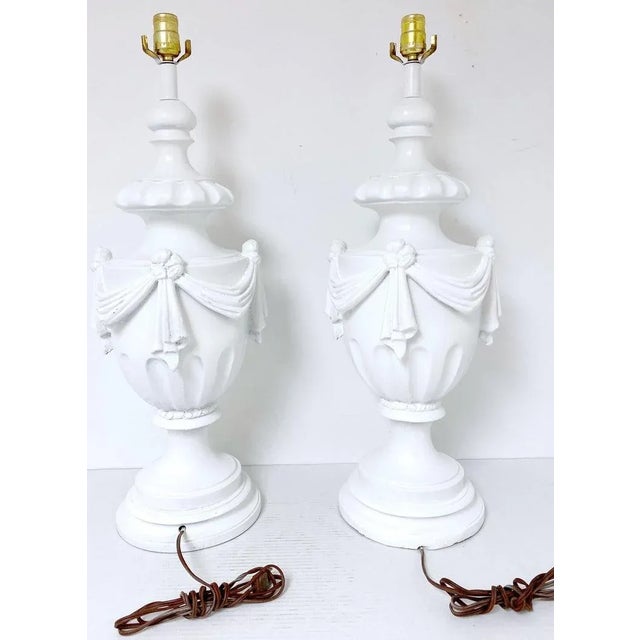 Large Pair of Hollywood Regency Neoclassical White Lacquered Draped Urn Lamps USA, Circa 1950s Add a touch of quiet...
