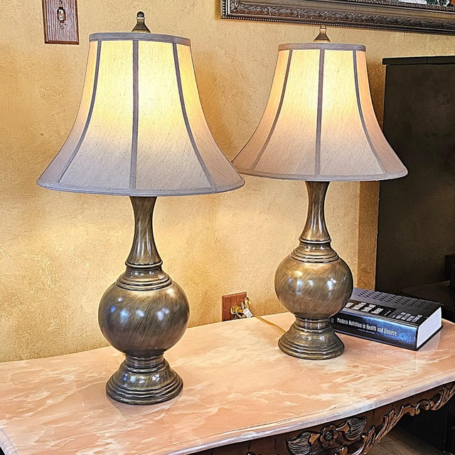 Pair of vintage traditional table lamps featuring elegantly proportioned urn-form bases with a brushed bronze finish and...