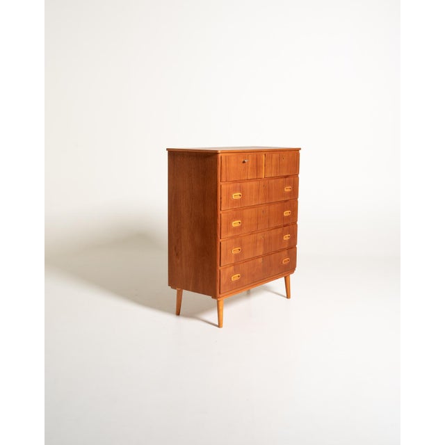 Teak frame with six drawers, two smaller ones at the top and four larger ones with oval oak handles. Tapered legs and a...