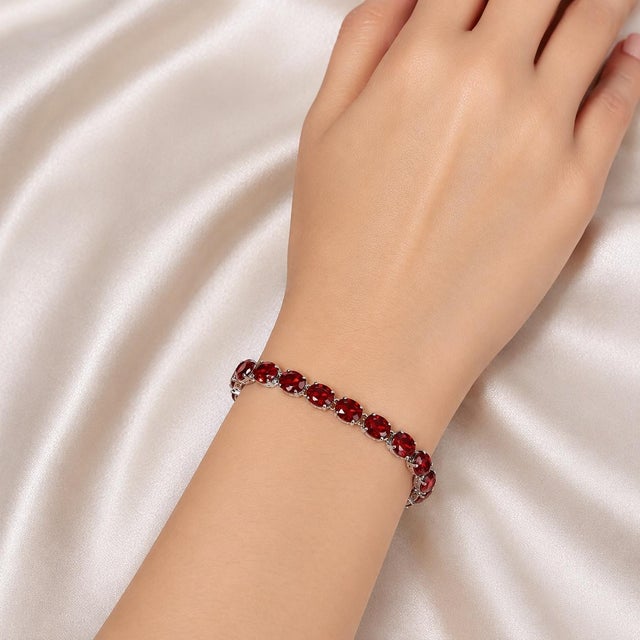 This sterling silver .925 flexible bracelet features numerous natural oval garnets totaling 20 carats. Measuring 7.75...