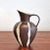 A compact pitcher vase with a classically inspired profile (model Nr. 2205/21). Glossy stripes of glaze in alternating...