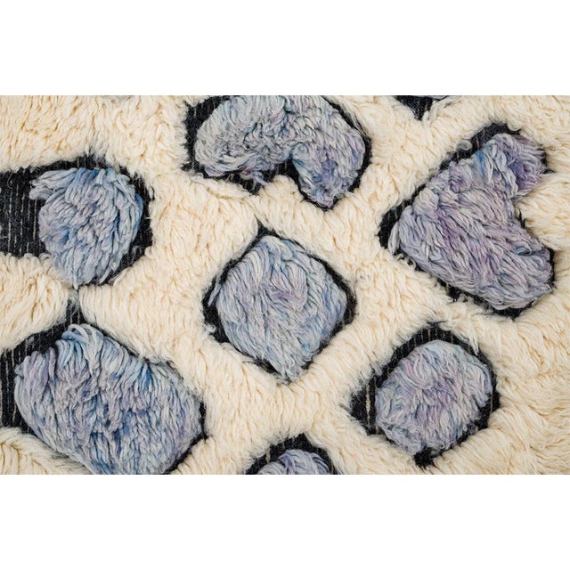 Calming hand-knotted wool rug in soft Ivory with bold Lavender Gray, Whispy Blue, and Gray Lilac geometric patterns,...