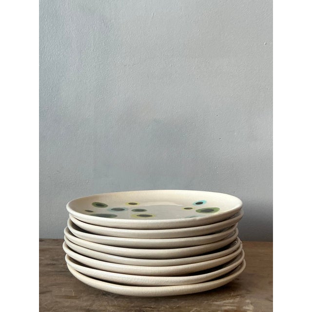 This striking set of eight vintage ceramic plates is a masterclass in artisanal Mediterranean charm, offering an...